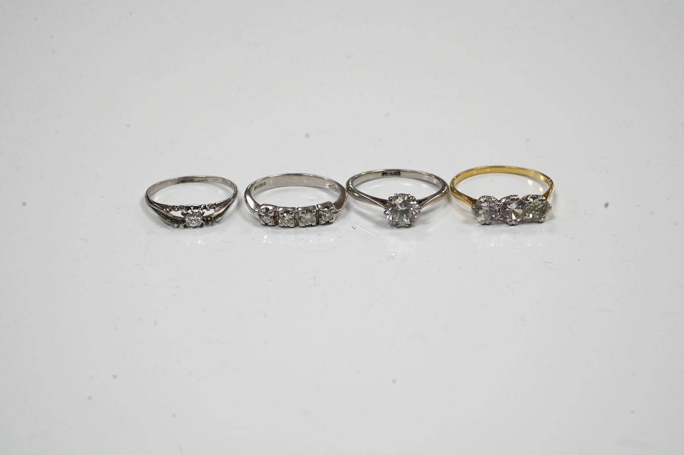 A 9ct gold and four stone diamond set ring, size L, a white metal and solitaire diamond ring and two simulated diamond rings. Condition - poor to fair